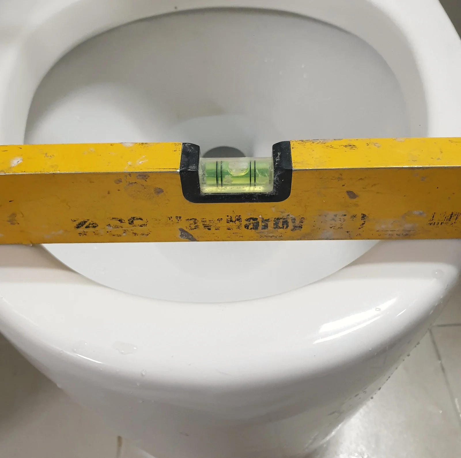 광명 변기백시멘트 재시공 깨져 흔들리던 변기, 수평·중심 잡고 실리콘으로 고정 1시간 작업 중 — 수평자를 올려 변기 수평과 중심 확인
